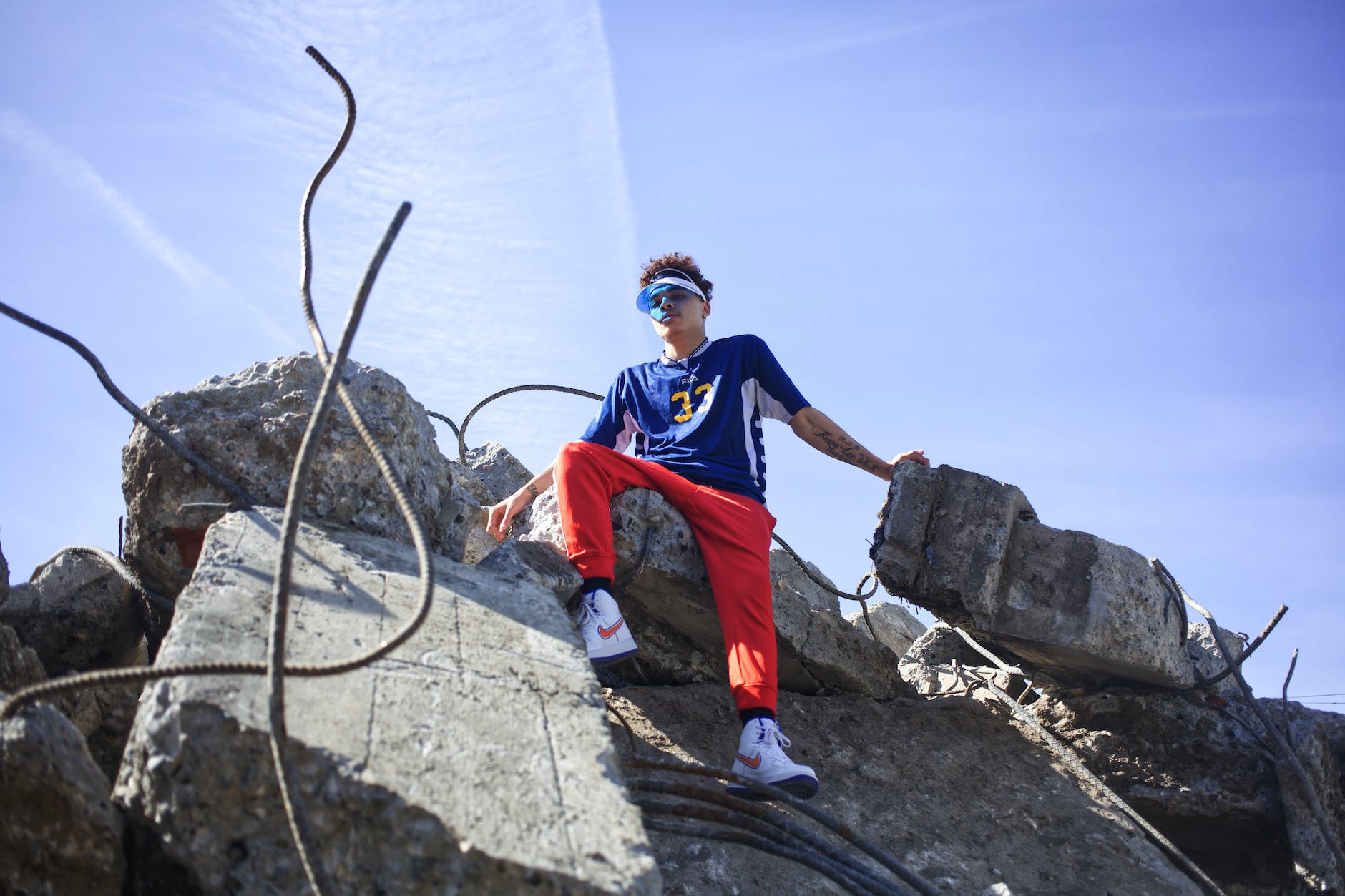 low angle shot of a young man in colorful active wear sitting on top of a pile of rubble