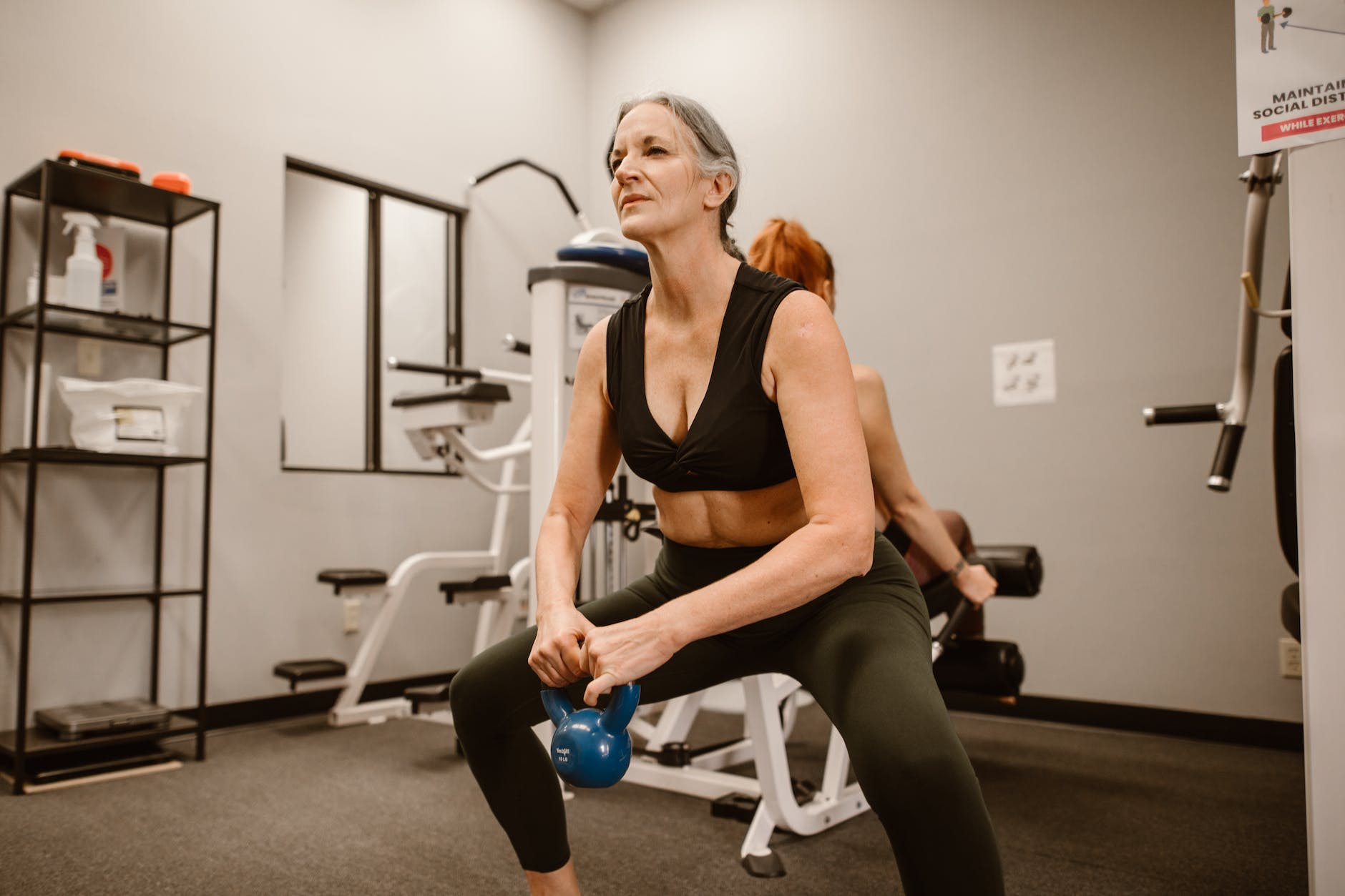 woman squatting while holding a kettle bell